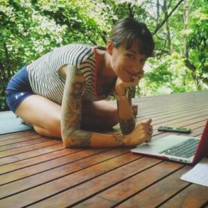 Joanne Highland at her laptop on a deck suspended in a forest